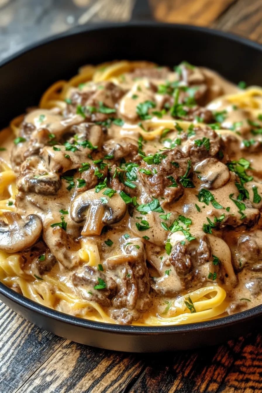 One-pot beef stroganoff with enoki mushrooms served in a rustic cast iron skillet.